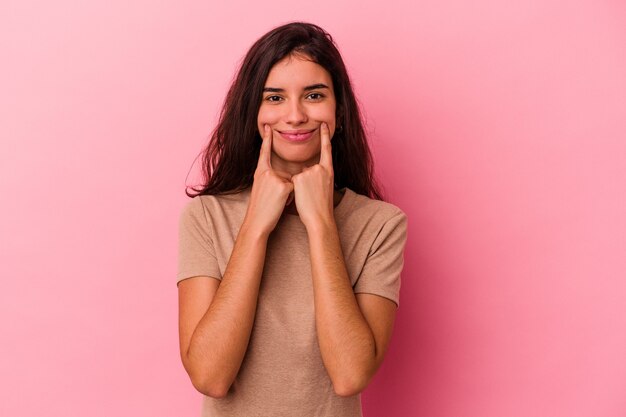 Jeune femme caucasienne isolée sur fond rose doutant entre deux options.