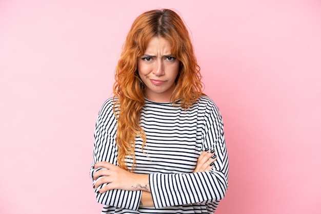 Une jeune femme caucasienne isolée sur un fond rose avec une expression malheureuse.