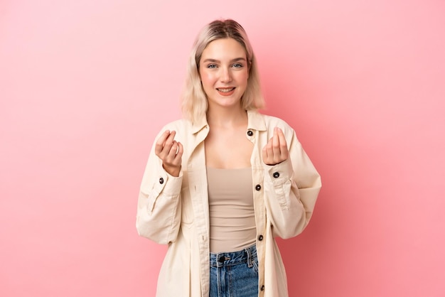 Jeune femme caucasienne isolée sur fond rose faisant un geste d'argent