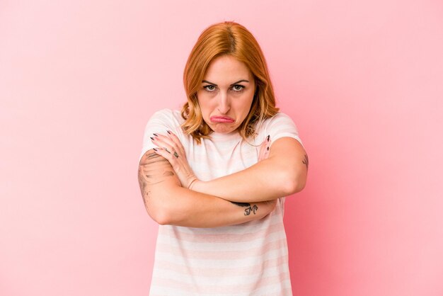 Jeune femme caucasienne isolée sur fond rose hausse les épaules et ouvre les yeux confus.