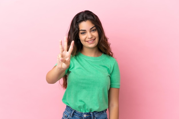 Jeune femme caucasienne isolée sur fond rose heureuse et comptant trois avec les doigts