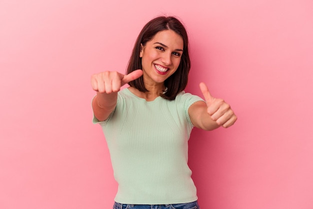 Jeune femme caucasienne isolée sur fond rose levant les deux pouces vers le haut souriant et confiant