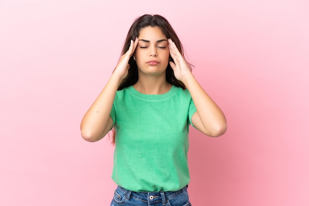 Jeune femme caucasienne isolée sur fond rose avec mal de tête