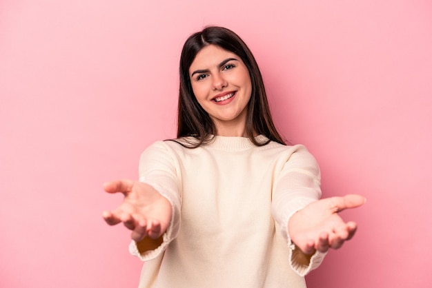 Jeune femme caucasienne isolée sur fond rose montrant une expression bienvenue