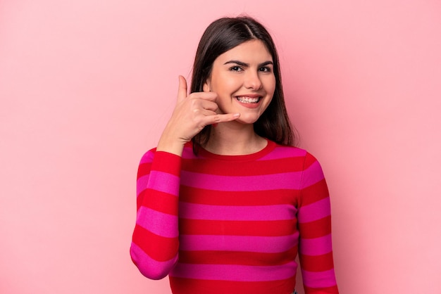 Jeune femme caucasienne isolée sur fond rose montrant un geste d'appel de téléphone portable avec les doigts