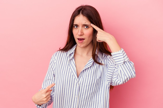 Jeune femme caucasienne isolée sur fond rose montrant un geste de déception avec l'index.