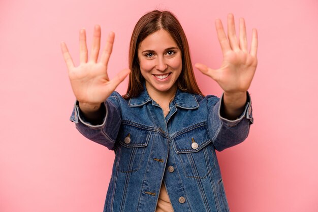 Jeune femme caucasienne isolée sur fond rose montrant le numéro dix avec les mains