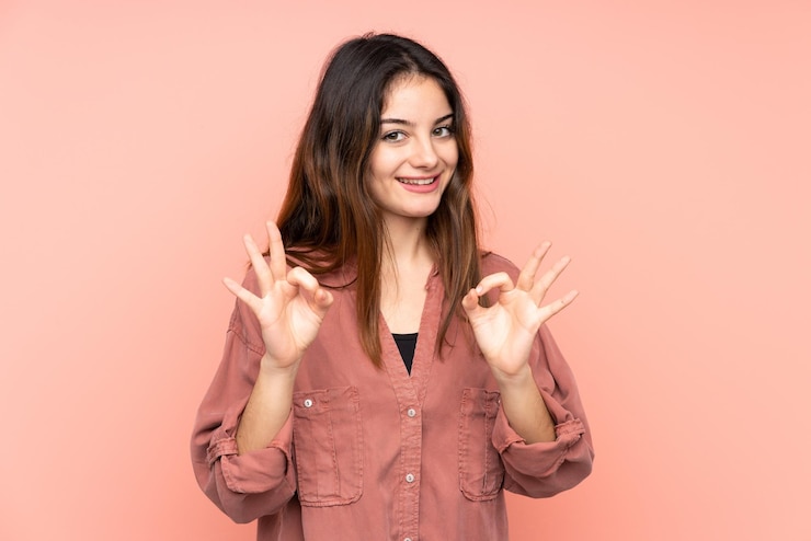 Photo une jeune femme caucasienne isolée sur un fond rose montrant un signe ok avec des doigts