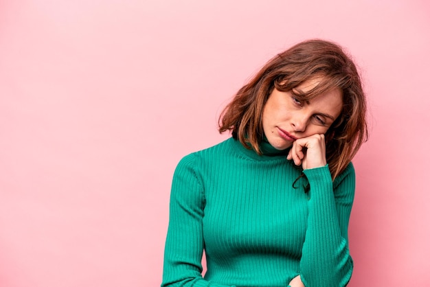 Jeune femme caucasienne isolée sur fond rose qui se sent triste et pensive en regardant l'espace de copie