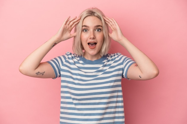 Jeune femme caucasienne isolée sur fond rose recevant une agréable surprise, excitée et levant les mains.