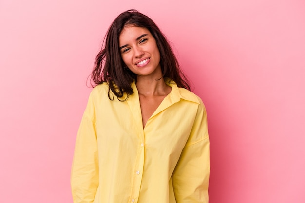 Jeune femme caucasienne isolée sur fond rose rit et ferme les yeux, se sent détendue et heureuse.