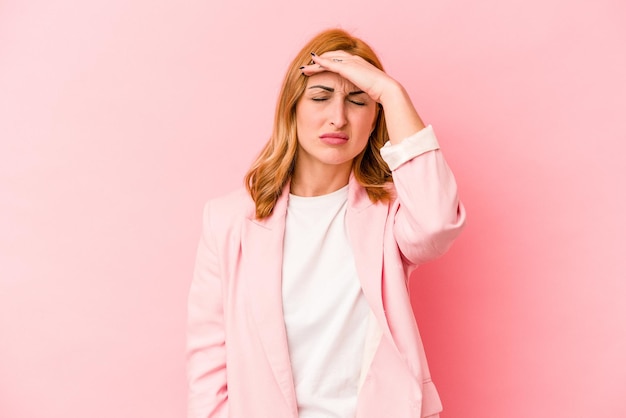 Jeune femme caucasienne isolée sur fond rose touchant les temples et ayant des maux de tête.