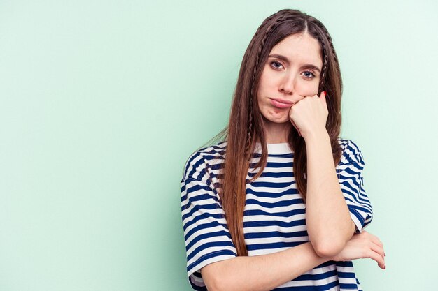 Jeune femme caucasienne isolée sur fond vert qui se sent triste et pensive en regardant l'espace de copie