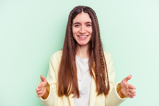 Jeune femme caucasienne isolée sur fond vert tenant quelque chose à deux mains, présentation du produit.