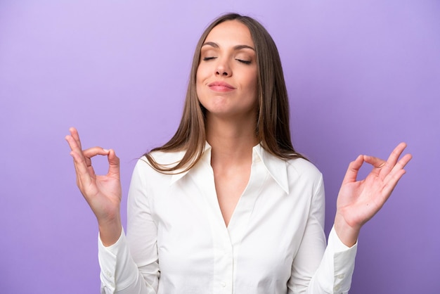 Jeune femme caucasienne isolée sur fond violet dans une pose zen