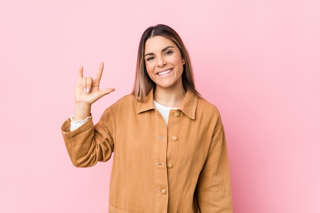 Jeune femme caucasienne isolée montrant un geste de cornes comme concept de révolution.