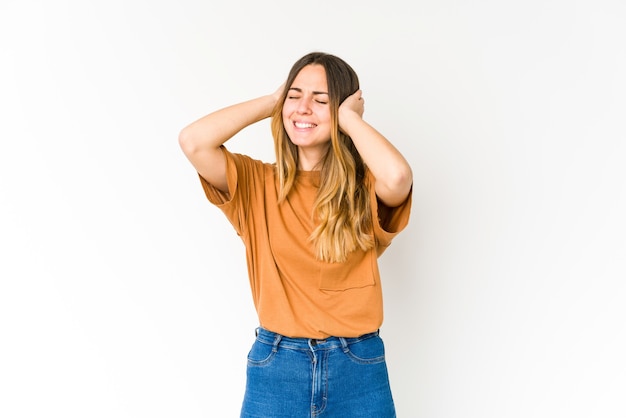 Jeune femme caucasienne isolée sur un mur blanc couvrant les oreilles avec les mains.