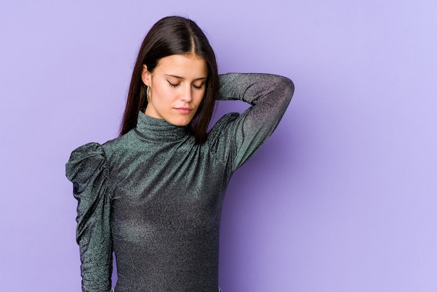 Jeune femme caucasienne isolée sur un mur violet ayant une douleur au cou due au stress, le massant et le touchant avec la main.