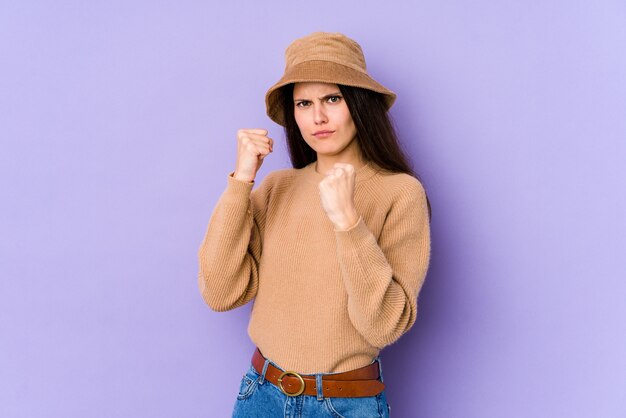 Jeune femme caucasienne isolée sur mur violet montrant le poing avec une expression faciale agressive.