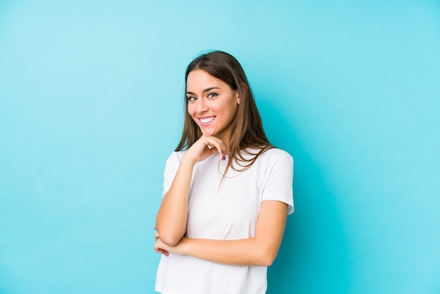 Jeune femme caucasienne isolée souriante heureuse et confiante, toucher le menton avec la main.