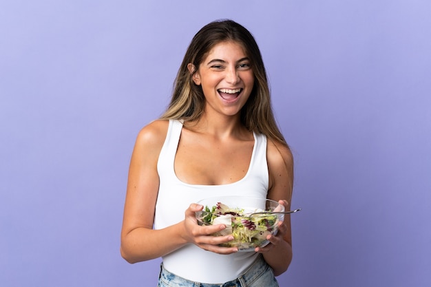 Jeune femme caucasienne isolée tenant un bol de salade en un clin d'oeil