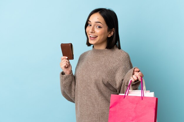 Jeune femme caucasienne isolée tenant des sacs à provisions et une carte de crédit