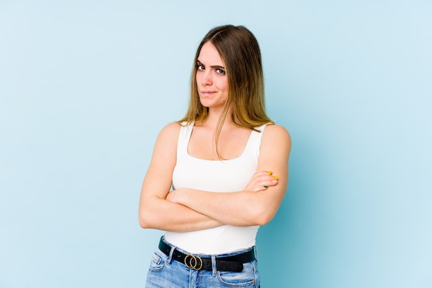 Jeune femme caucasienne isolée sur le visage bleu froncer les sourcils de mécontentement, garde les bras croisés.