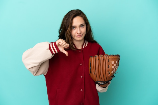 Jeune femme caucasienne jouant au baseball isolé sur fond bleu montrant le pouce vers le bas avec une expression négative