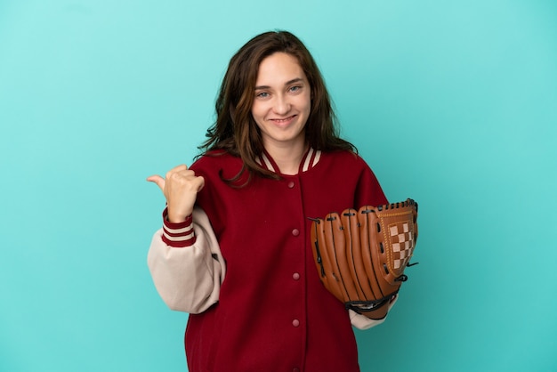 Jeune femme caucasienne jouant au baseball isolé sur fond bleu pointant vers le côté pour présenter un produit