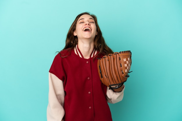 Jeune femme caucasienne jouant au baseball isolé sur fond bleu en riant