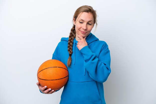 Jeune femme caucasienne jouant au basket isolé sur fond blanc regardant sur le côté et souriant