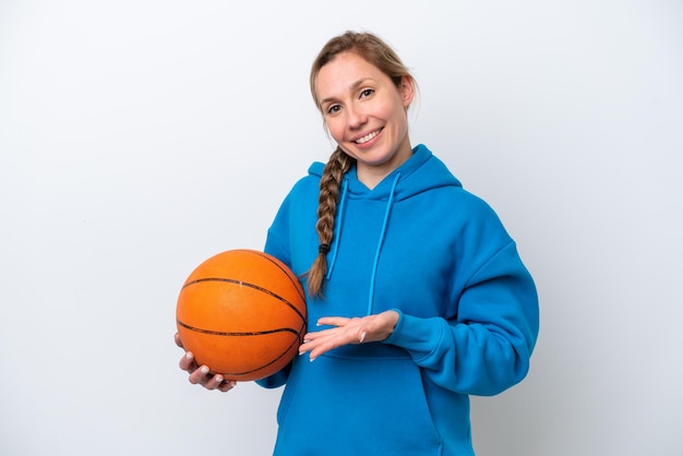 Jeune femme caucasienne jouant au basket isolé sur fond blanc tendant les mains sur le côté pour inviter à venir