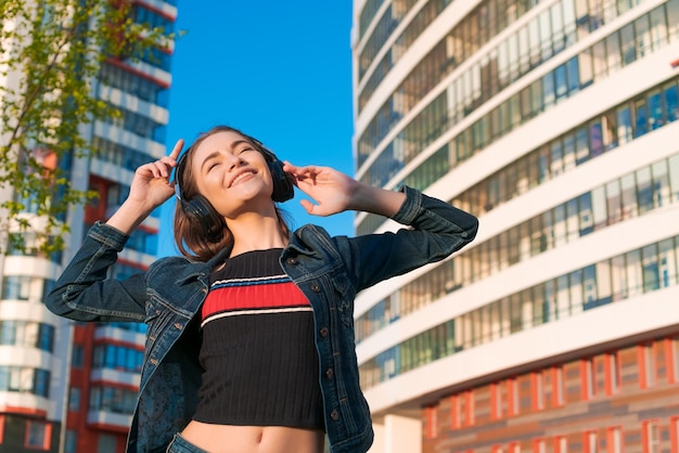 Jeune femme caucasienne joyeuse et énergique portant des écouteurs Vêtue d'un denim