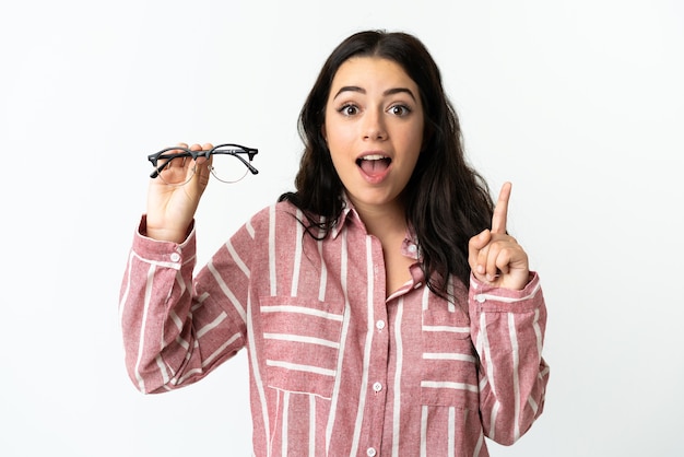 Jeune femme caucasienne avec des lunettes isolé sur fond blanc pointant vers le haut une excellente idée