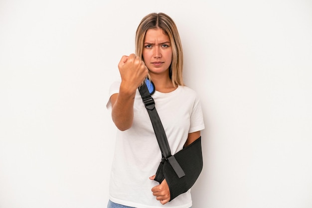 Jeune femme caucasienne avec main cassée isolée sur fond blanc montrant le poing à la caméra, expression faciale agressive.