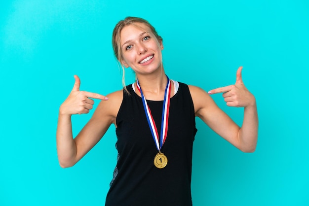 Jeune femme caucasienne avec des médailles isolées sur fond bleu fière et satisfaite