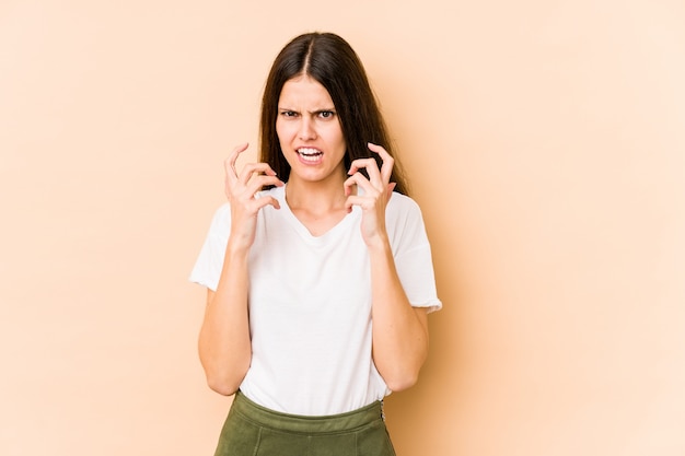 Jeune femme caucasienne sur mur beige bouleversé crier avec les mains tendues.