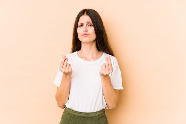 Jeune femme caucasienne sur mur beige montrant qu'elle n'a pas d'argent.