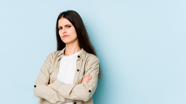 Jeune femme caucasienne sur mur bleu suspect, incertain, vous examine.