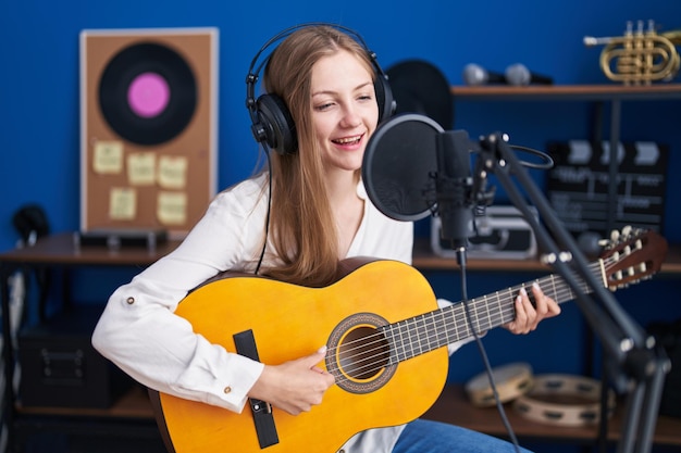 Jeune femme caucasienne musicienne chantant une chanson jouant de la guitare classique au studio de musique