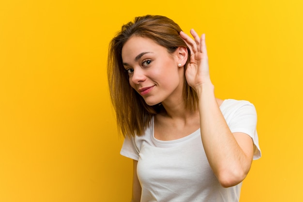 Jeune femme caucasienne naturelle essayant d'écouter un potin.