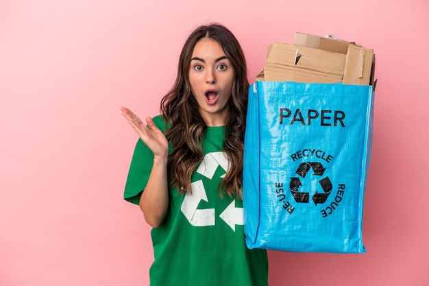 Jeune femme caucasienne papier recyclé isolé sur fond rose surpris et choqué.