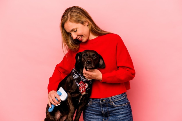 Jeune femme caucasienne peignant le chien isolé sur fond rose