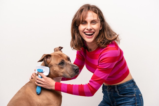 Jeune femme caucasienne peignant son chien isolé sur fond blanc