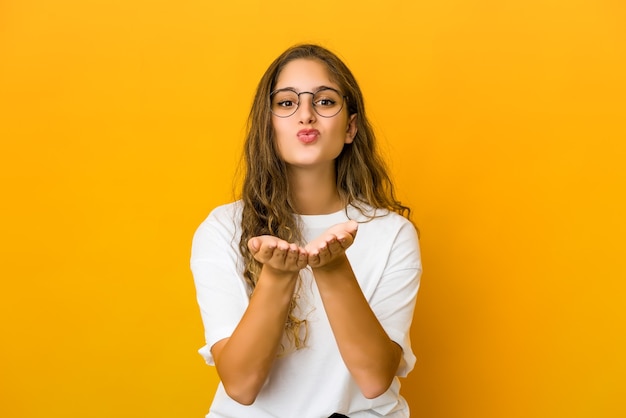 Jeune femme caucasienne pliant les lèvres et tenant les paumes pour envoyer un baiser d'air.