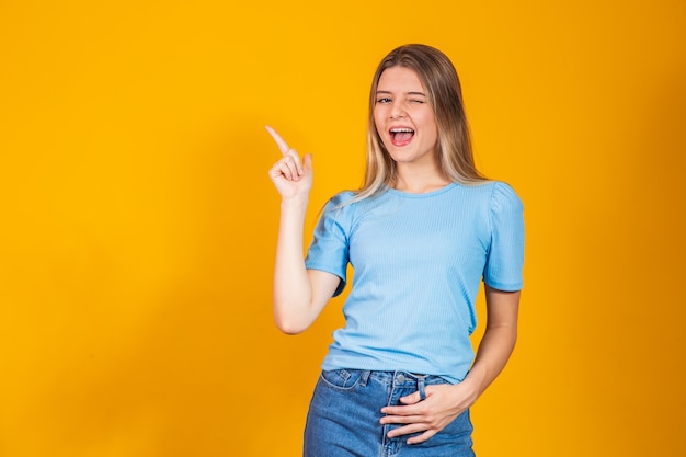 Jeune femme caucasienne pointant sur le côté avec un espace libre pour le texte et la bouche ouverte.