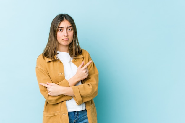 Jeune femme caucasienne pointe sur le côté, essaie de choisir entre deux options.