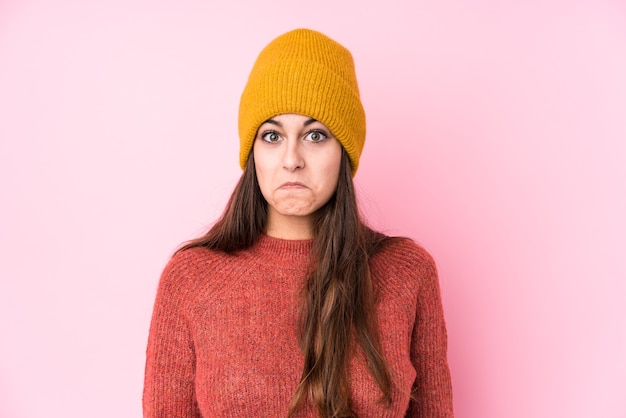 Jeune femme caucasienne portant un bonnet de laine hausse les épaules et les yeux ouverts confus.