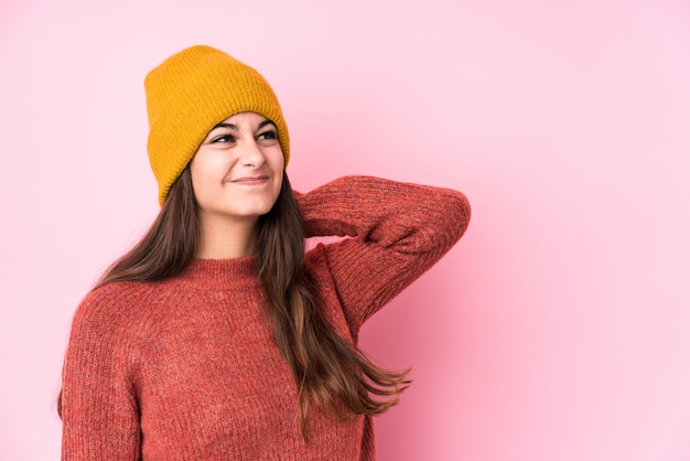 Jeune femme caucasienne portant un bonnet de laine touchant l'arrière de la tête, pensant et faisant un choix.