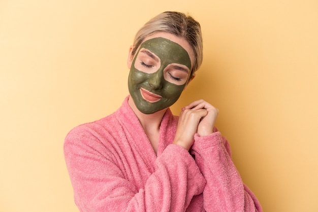 Jeune femme caucasienne portant un masque facial isolé sur fond jaune